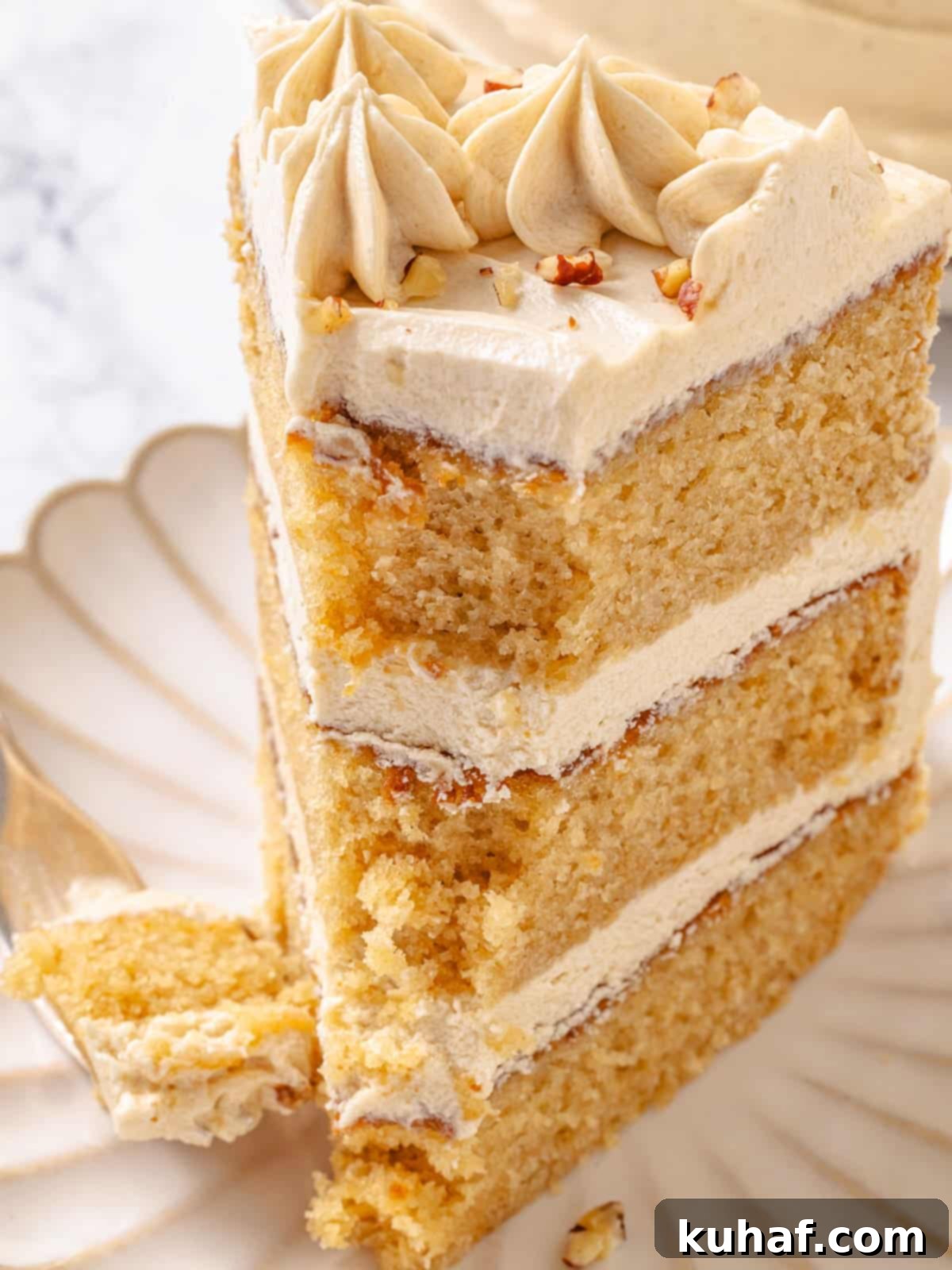 Pure Maple Indulgence 2 Fork holding a bite of three-layered maple cake with fluffy maple frosting between each layer, showing the moist texture.