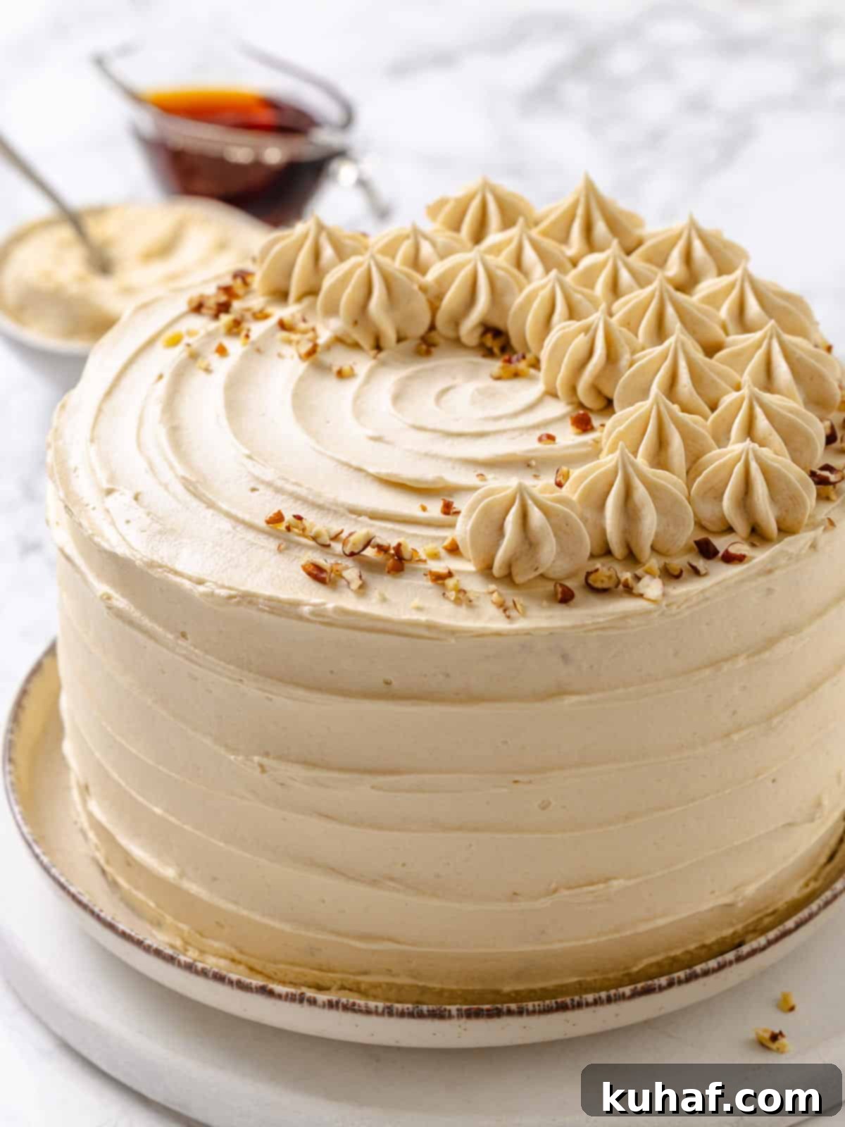 Pure Maple Indulgence 18 A perfectly sliced piece of maple cake with visible layers of cake and fluffy frosting, presented on a white plate, ready to be enjoyed.