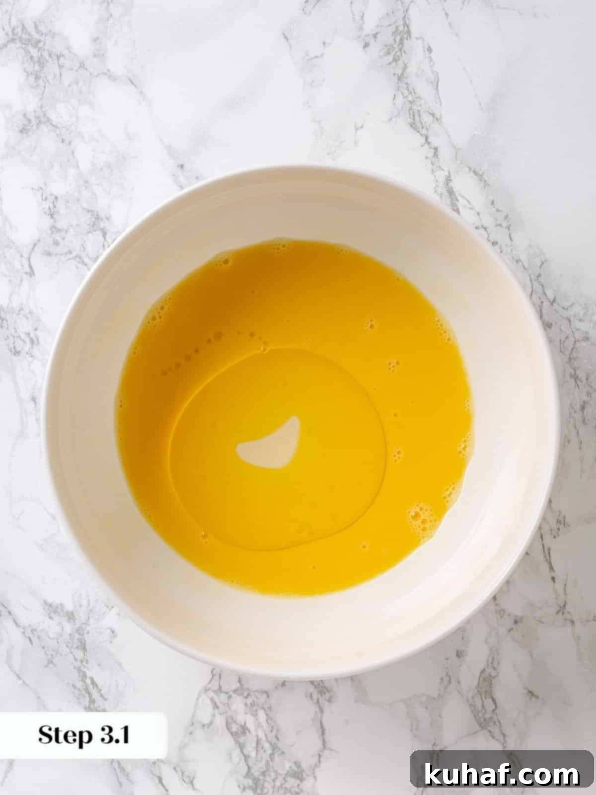 Pure Maple Indulgence 6 Slowly pouring neutral vegetable oil into whisked eggs in a mixing bowl to create a smooth emulsion for the maple cake batter.