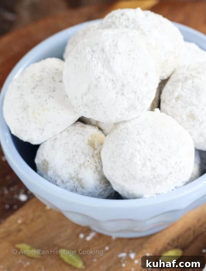 Melt-Away Cardamom Walnut Snowballs 2 Close-up of Cardamom Walnut Snowball Cookies coated in powdered sugar, showcasing their crumbly texture and festive appeal.