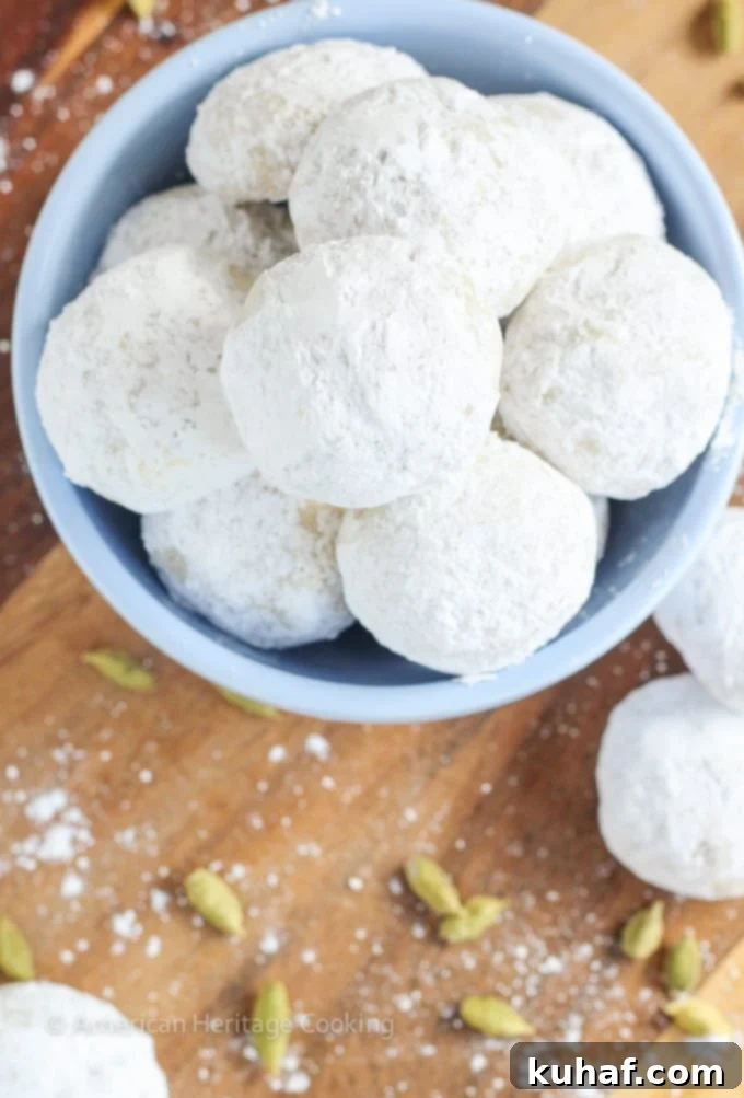 Melt-Away Cardamom Walnut Snowballs 3 Delicious Cardamom Walnut Snowballs piled high, showcasing the generous coating of powdered sugar and inviting texture.