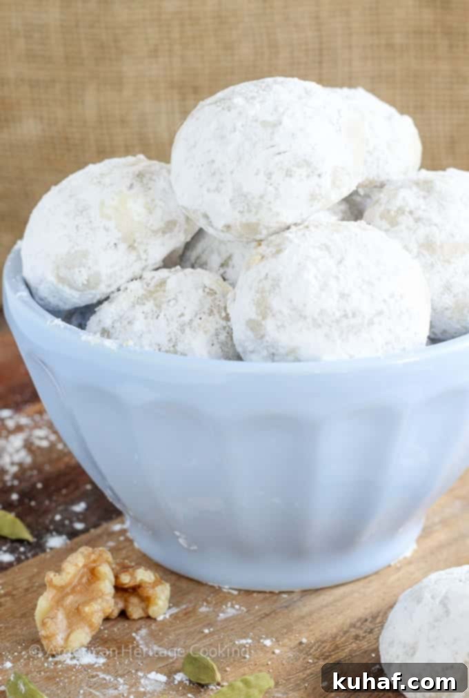 Melt-Away Cardamom Walnut Snowballs 4 A trio of Cardamom Walnut Snowballs, showcasing their round shape and snowy powdered sugar coating, perfect for holiday gatherings.