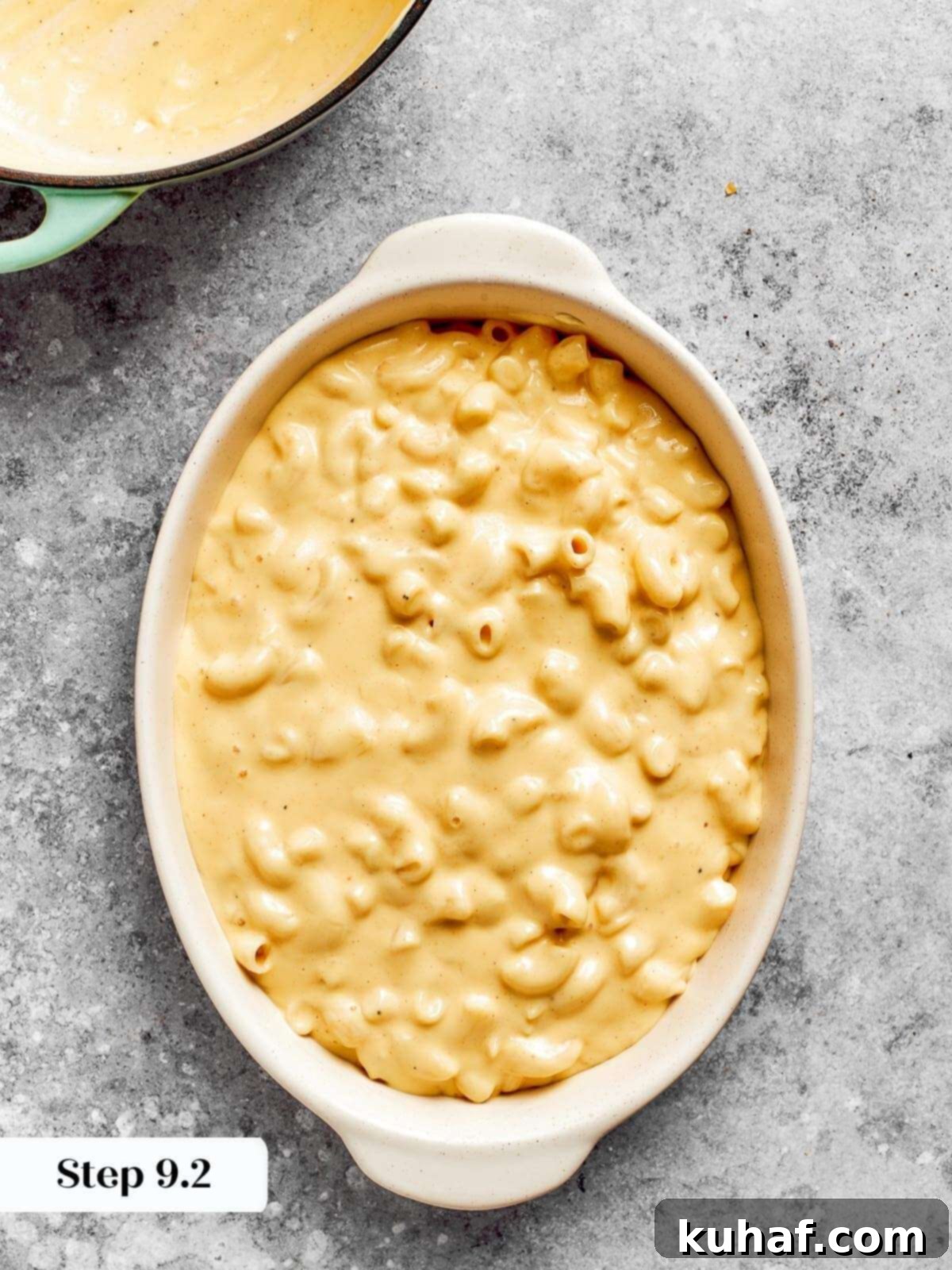 Elbow macaroni, glistening with creamy cheese sauce, settled into a baking dish before the final oven bake.