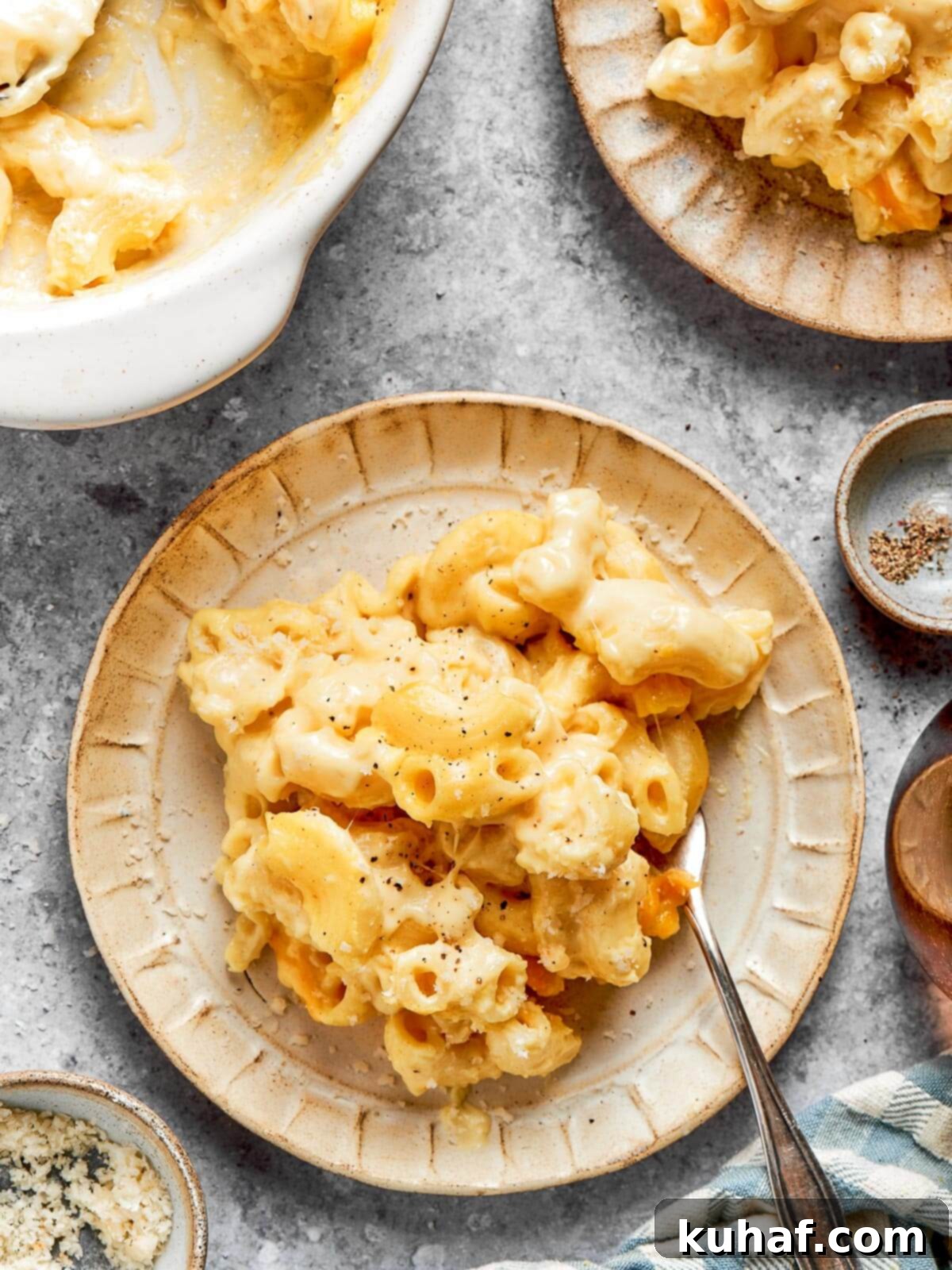 A close-up of a plate of perfectly cheesy baked mac and cheese, ready to be enjoyed, with a spoon nearby.