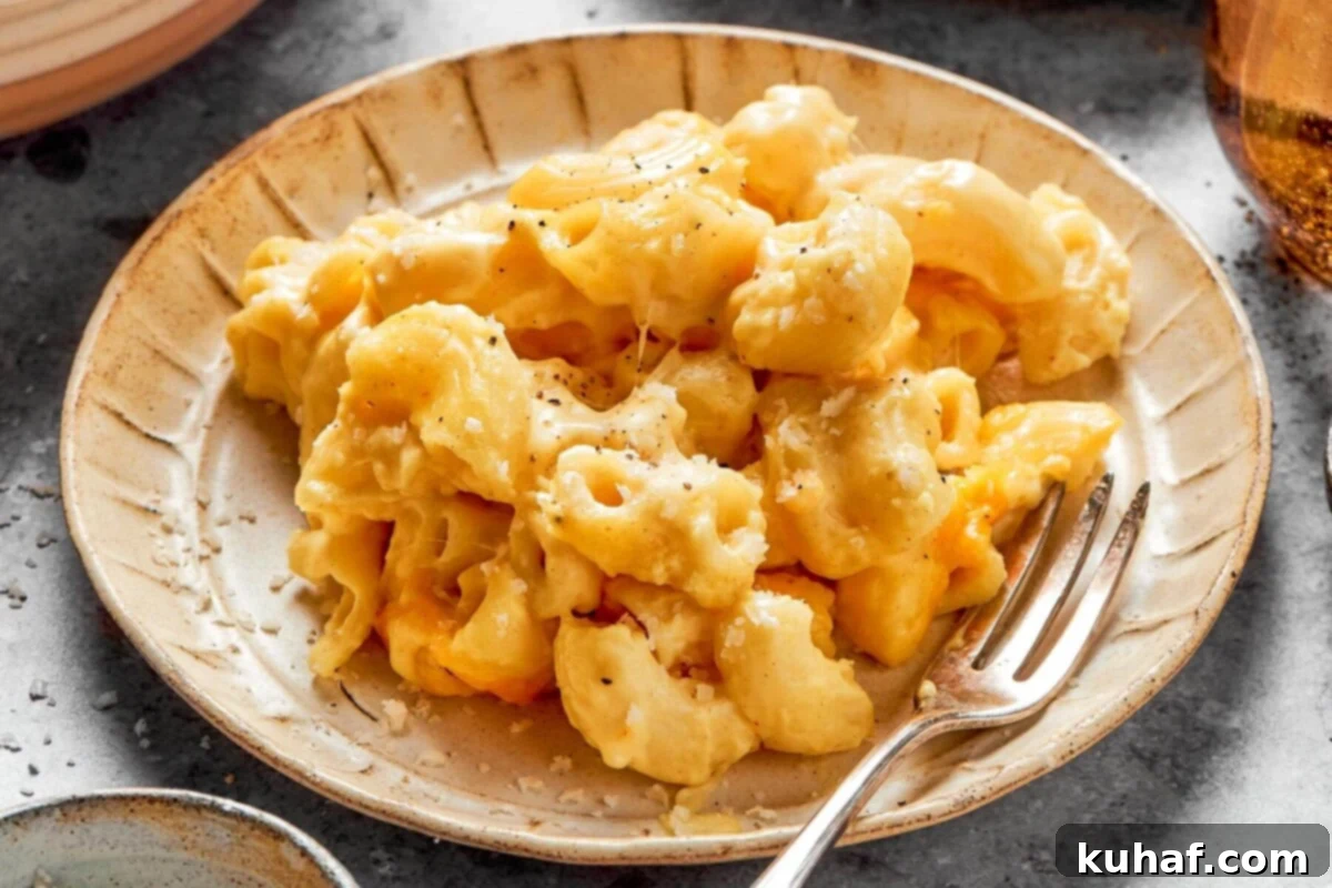 A serving of baked mac and cheese being scooped directly from the hot casserole dish, showing the creamy, gooey texture.