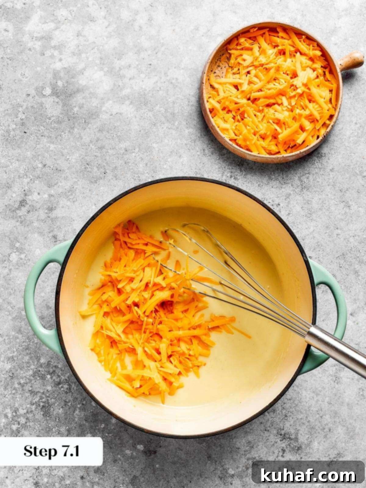 Generous amounts of freshly shredded cheddar cheese melting beautifully into the warm, thickened roux, creating a cohesive, creamy sauce.