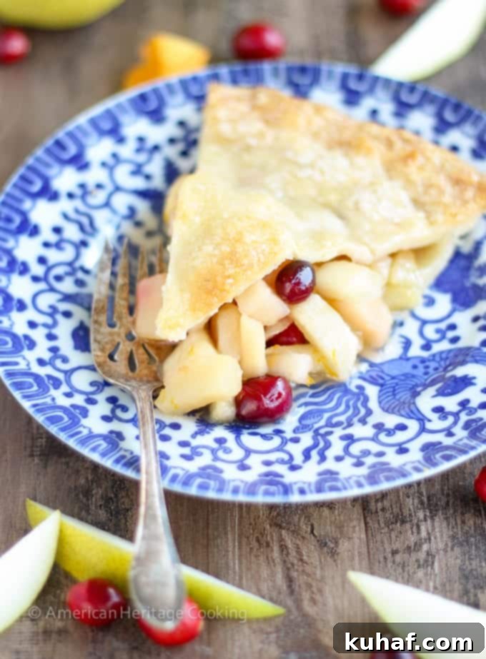 A perfectly baked slice of Cranberry Orange Pear Pie, showcasing the vibrant fruit filling and golden, flaky crust.