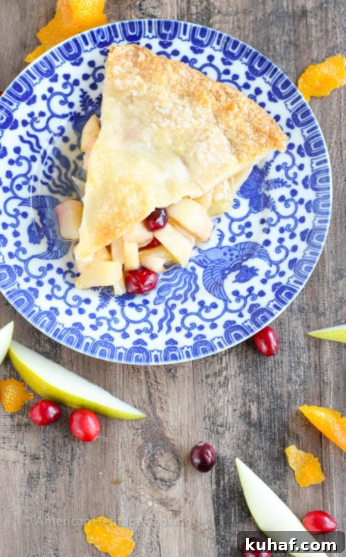 A beautifully golden-brown Cranberry Orange Pear Pie, fresh out of the oven, with a rustic crimped crust.