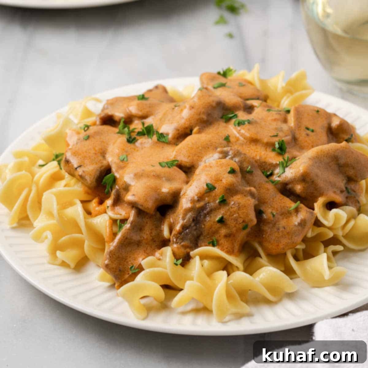 Plated beef stroganoff with a glass of red wine, ready for a cozy dinner.