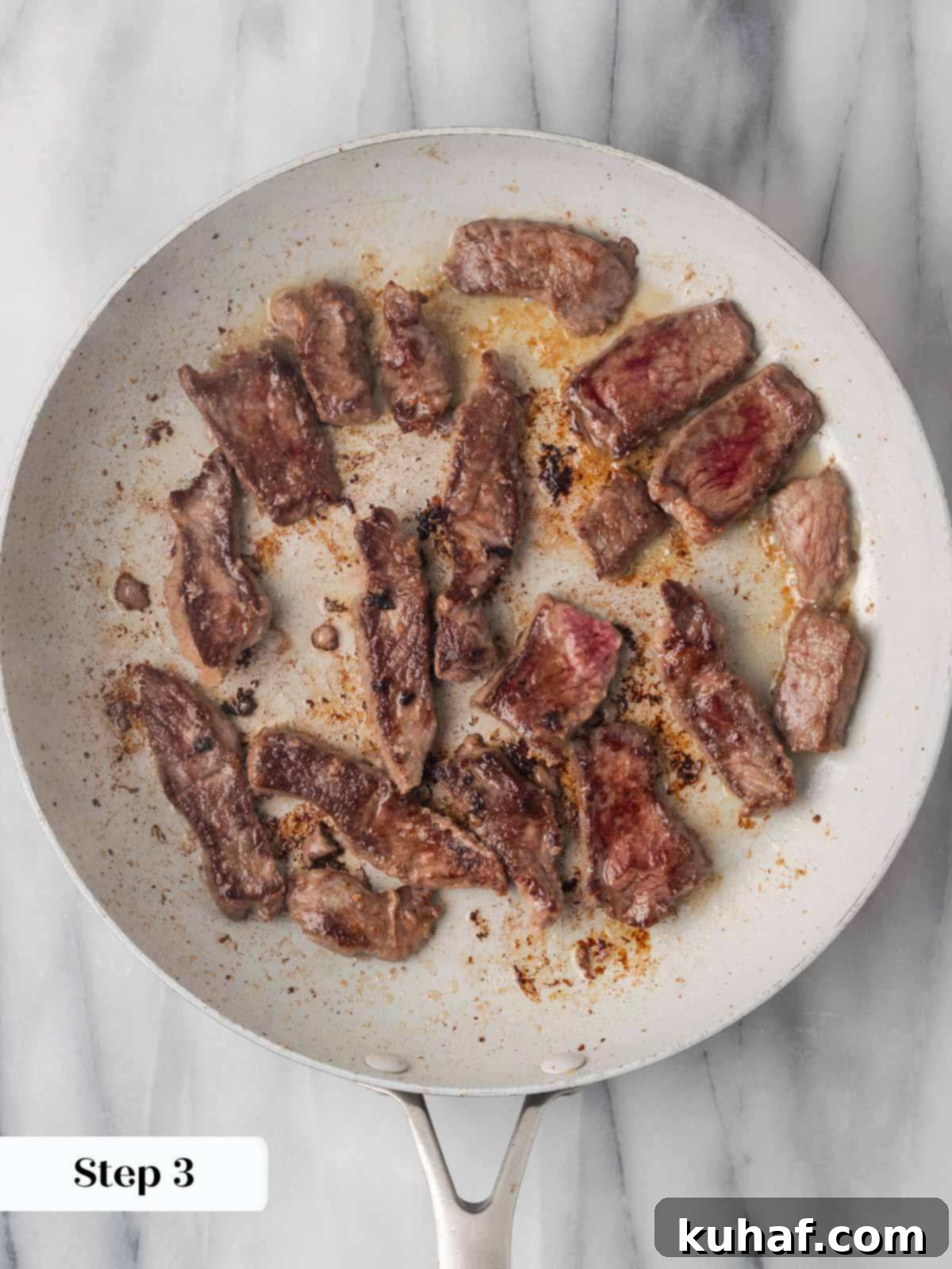 Seared sirloin steak strips in a hot pan, developing a golden crust.