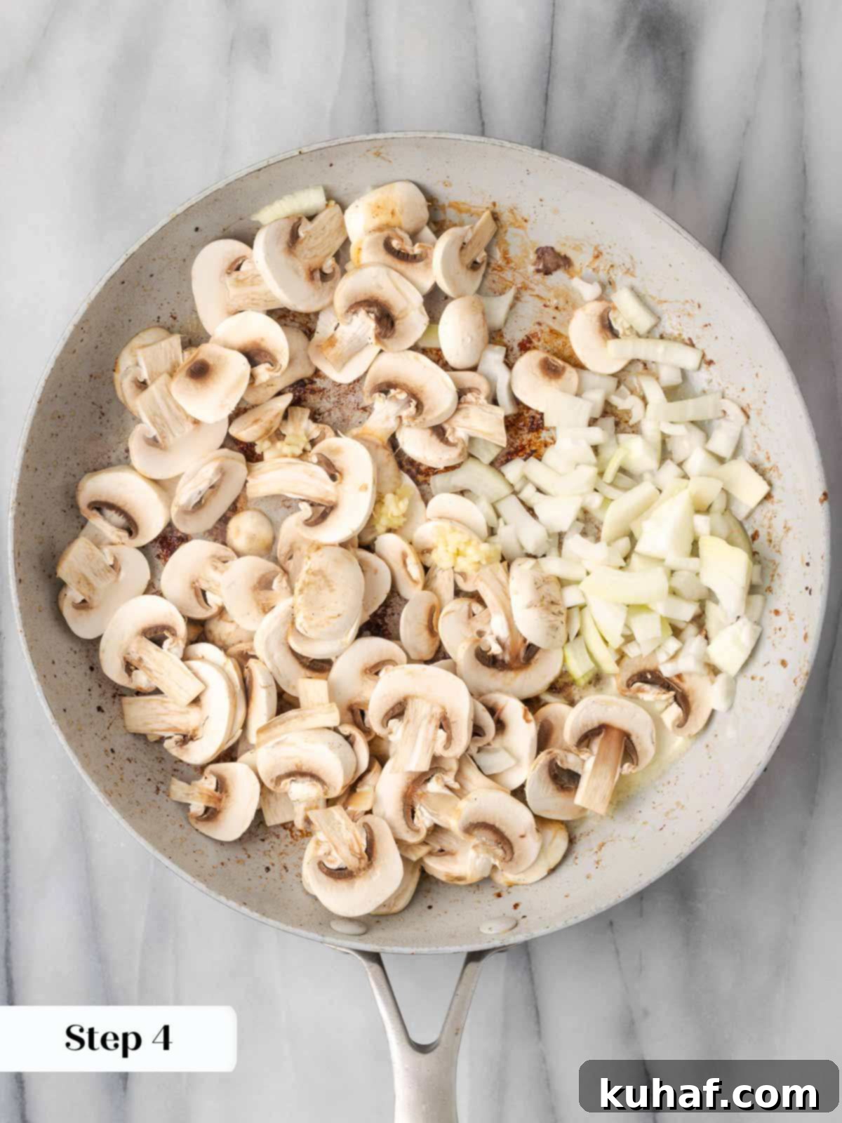 Mushrooms and onions cooking in a skillet, softening and turning golden.