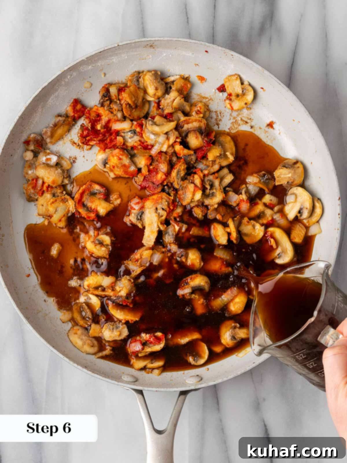 Adding beef broth to the rich sauce, stirring to combine.
