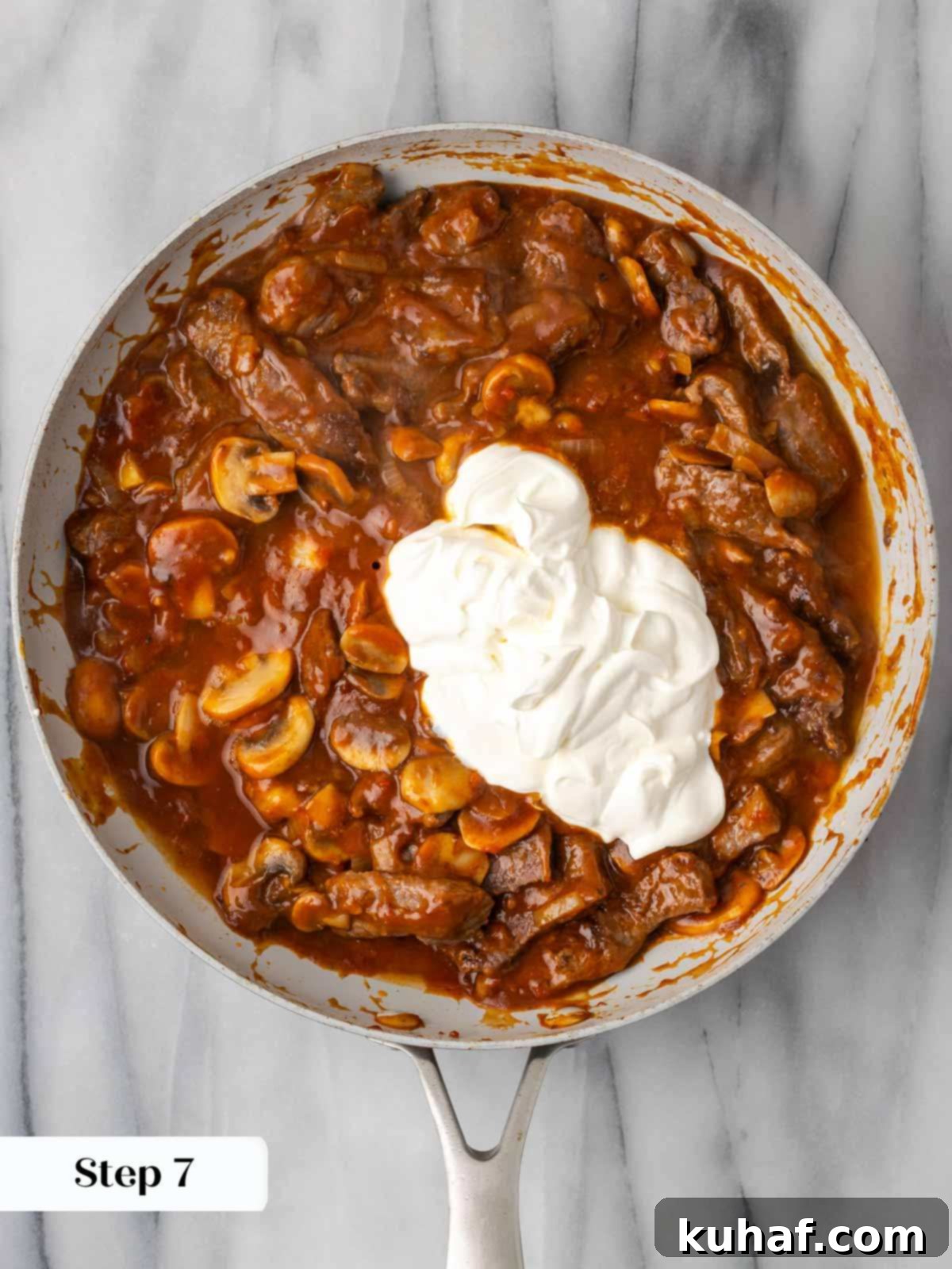 Adding sour cream to finish the beef stroganoff, creating a creamy texture.