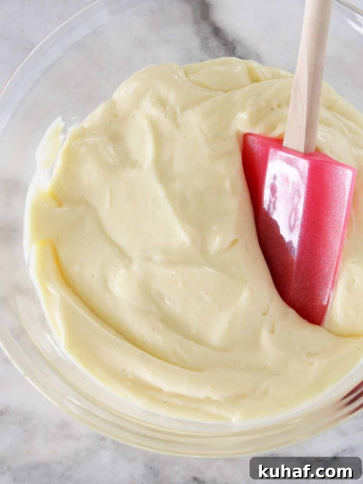 Silky smooth vanilla pastry cream on a marble counter, ready for use as a dessert filling.
