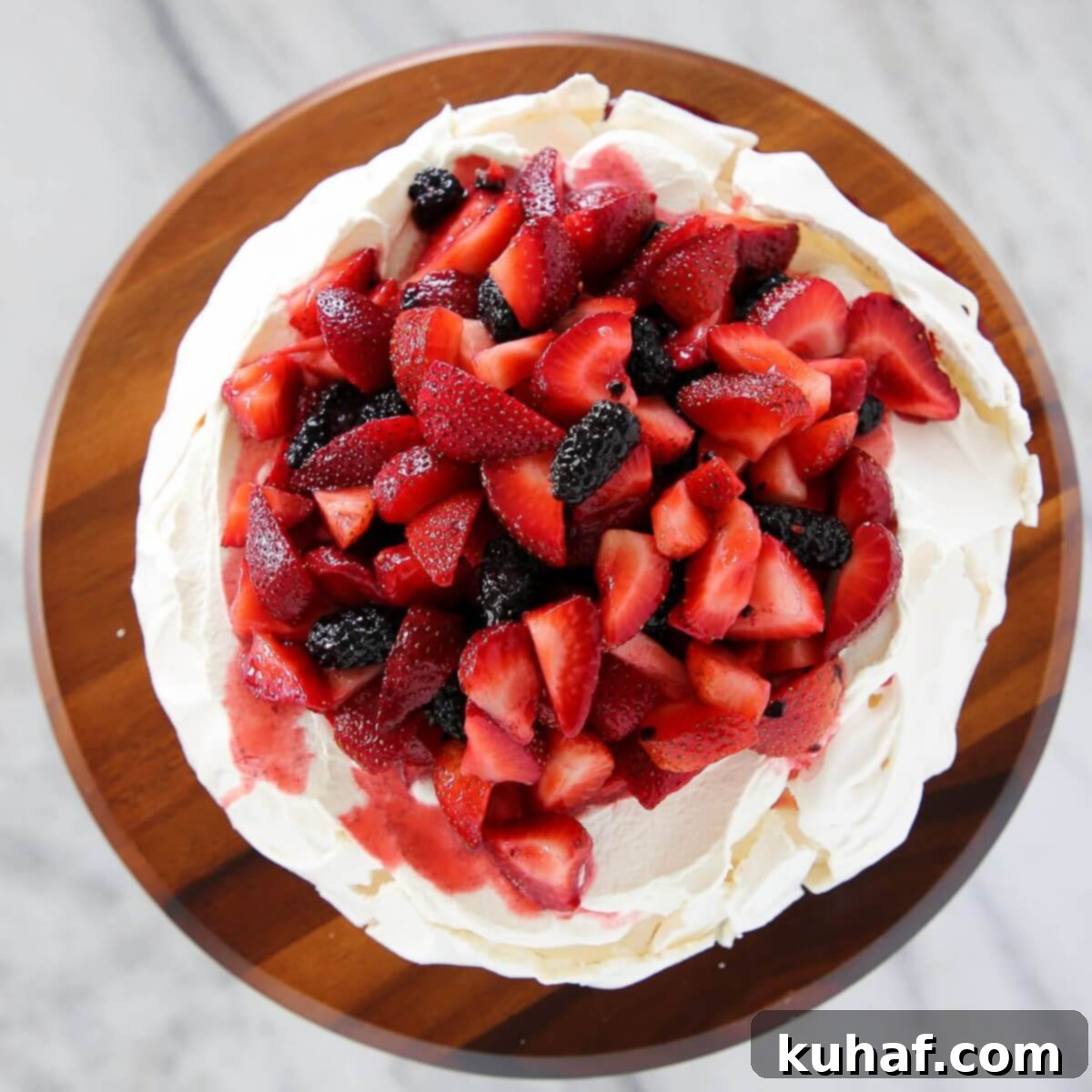 Lemon berry pavlova cake on a marble countertop.