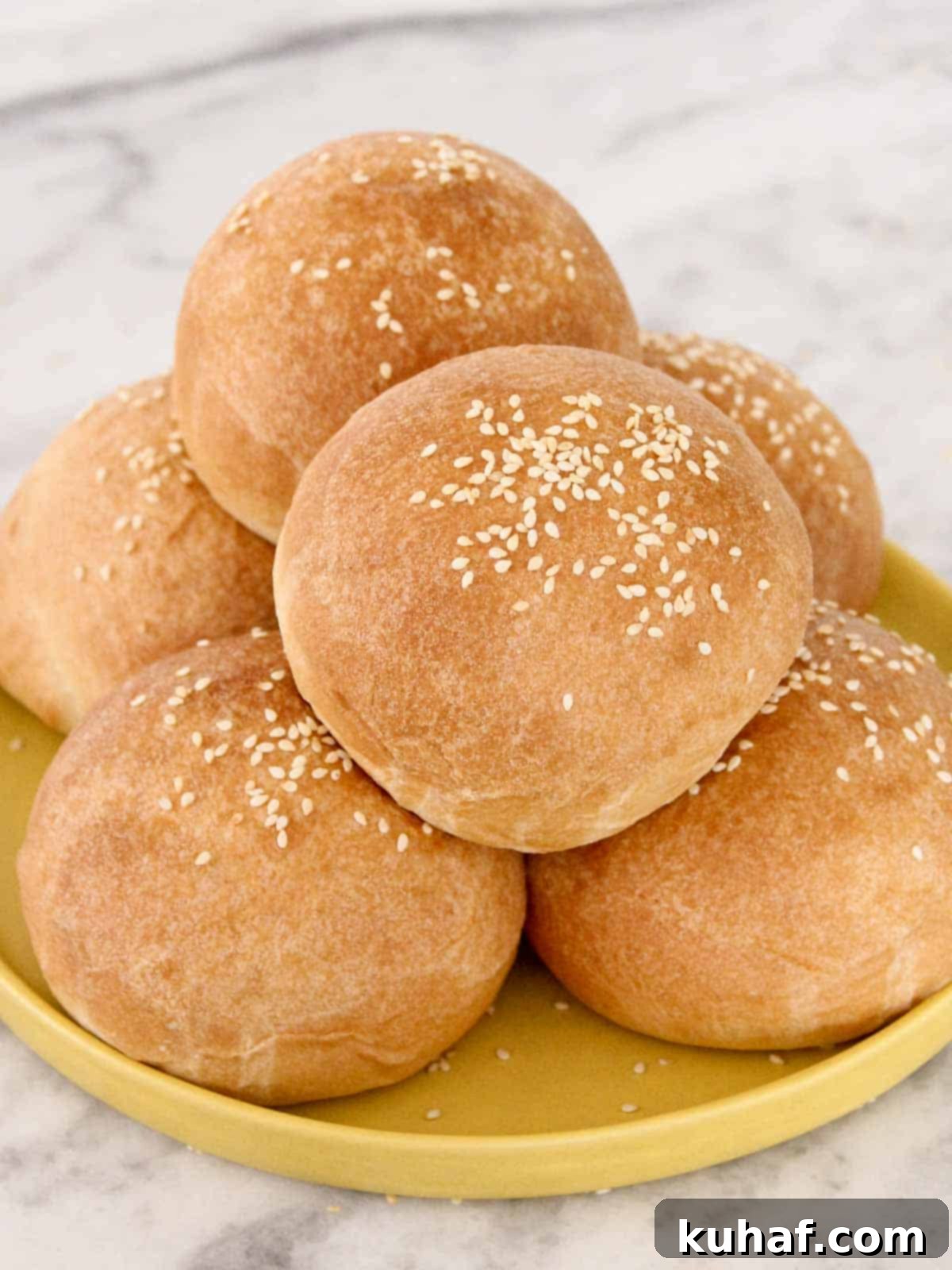 hamburger buns with sesame seeds on yellow plate. 