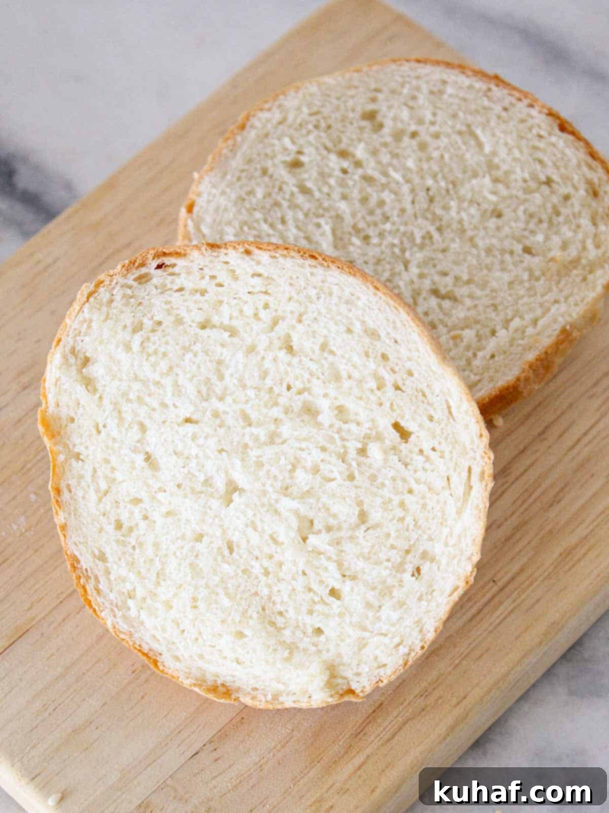 brioche bun sliced open on wooden board.