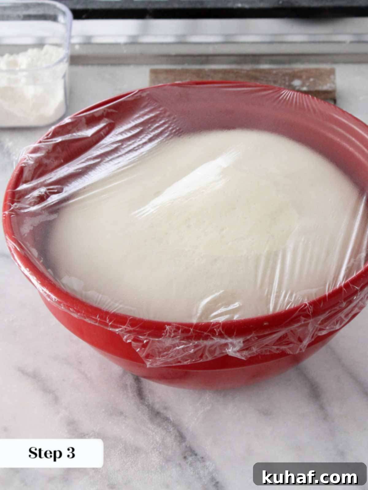 proofed brioche dough in red bowl.