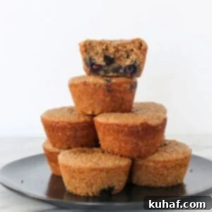 A banana protein muffin with one bite taken, stacked with others to show soft inside texture.