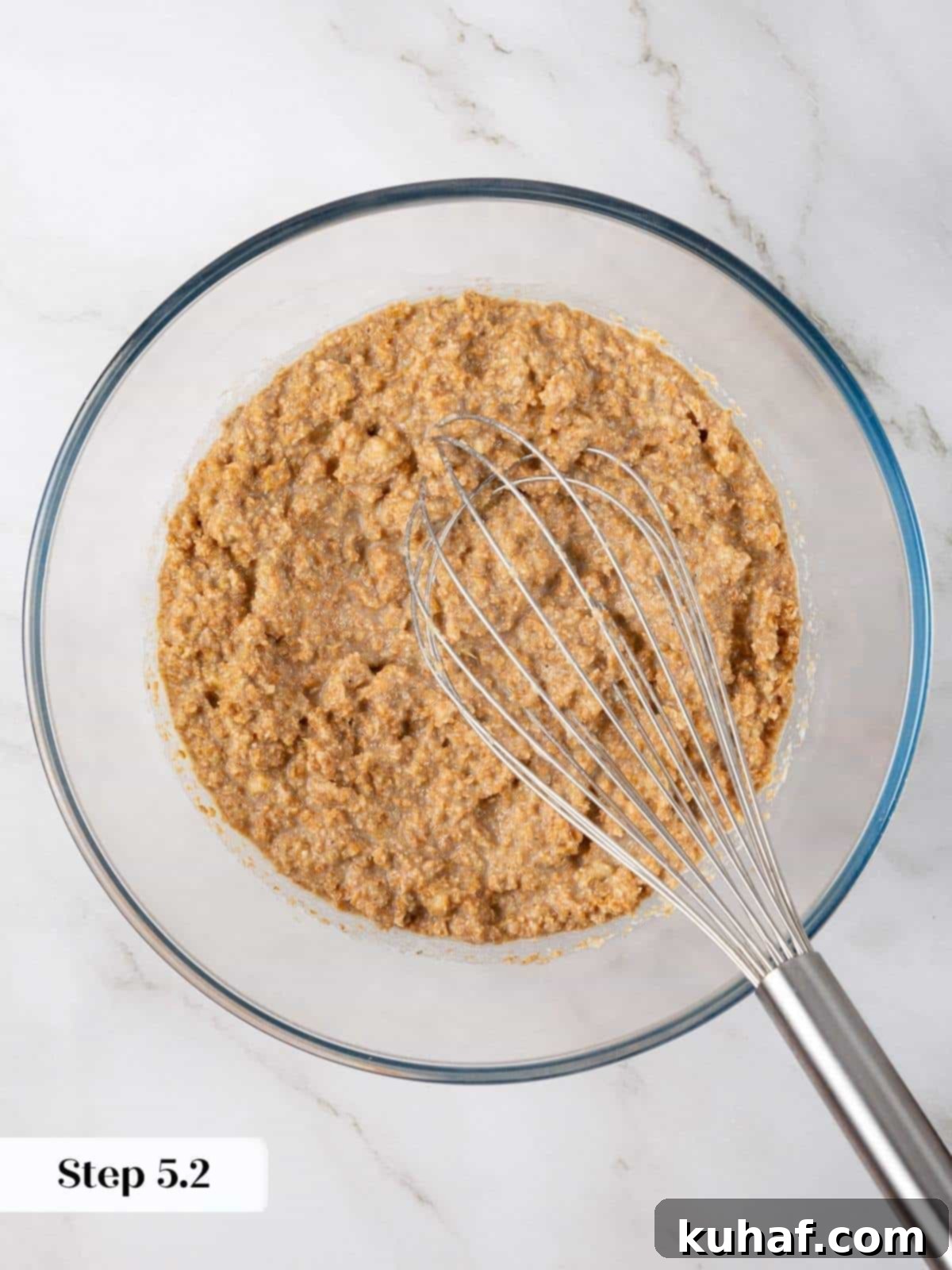 Wet ingredients including mashed banana, oil, and eggs mixed together until smooth for muffin batter.