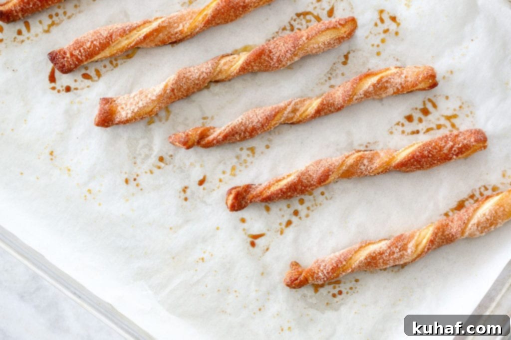 Sugary Cinnamon Spirals 2 Golden brown Cinnamon Sugar Twists on a baking sheet, ready to be enjoyed. A perfect easy puff pastry dessert for any occasion.