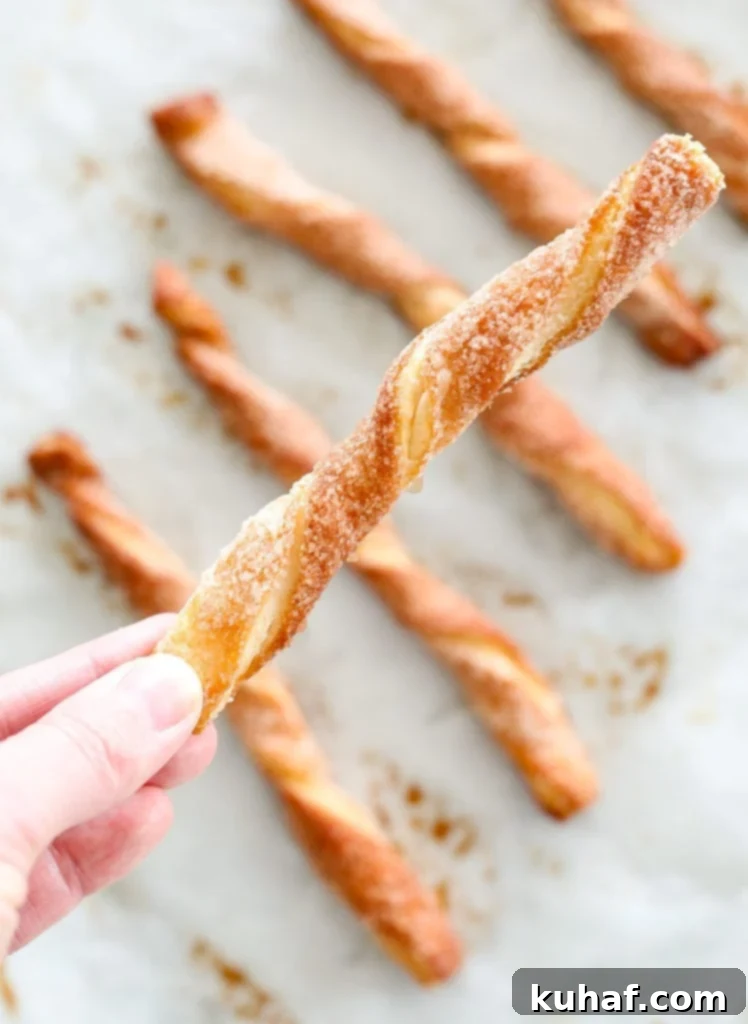 Sugary Cinnamon Spirals 3 Close-up of golden brown Cinnamon Sugar Twists cooling on parchment paper after baking. Highlighting the crispy sugar coating.