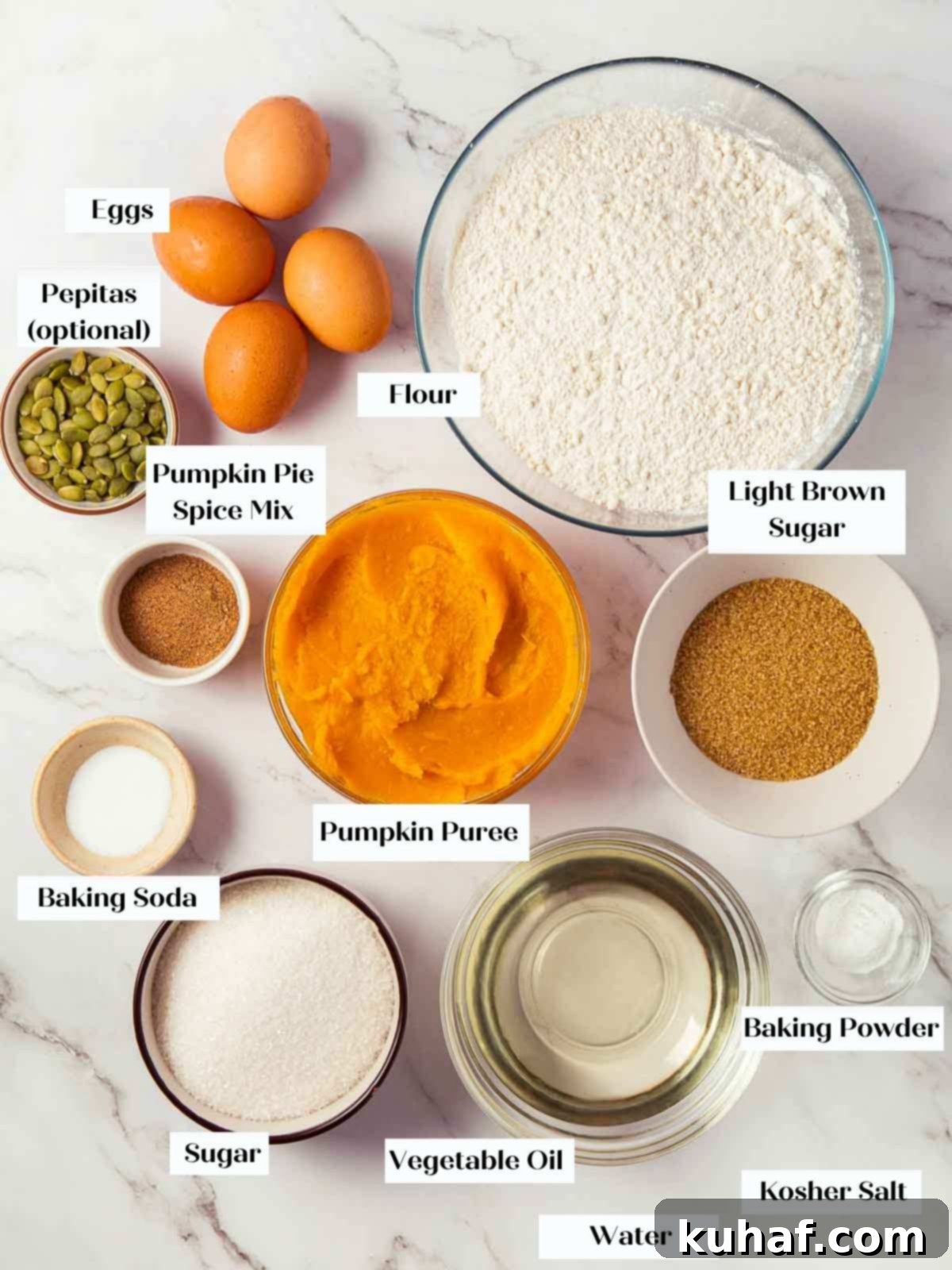 Ingredients for pumpkin bread arranged on a white marble countertop.