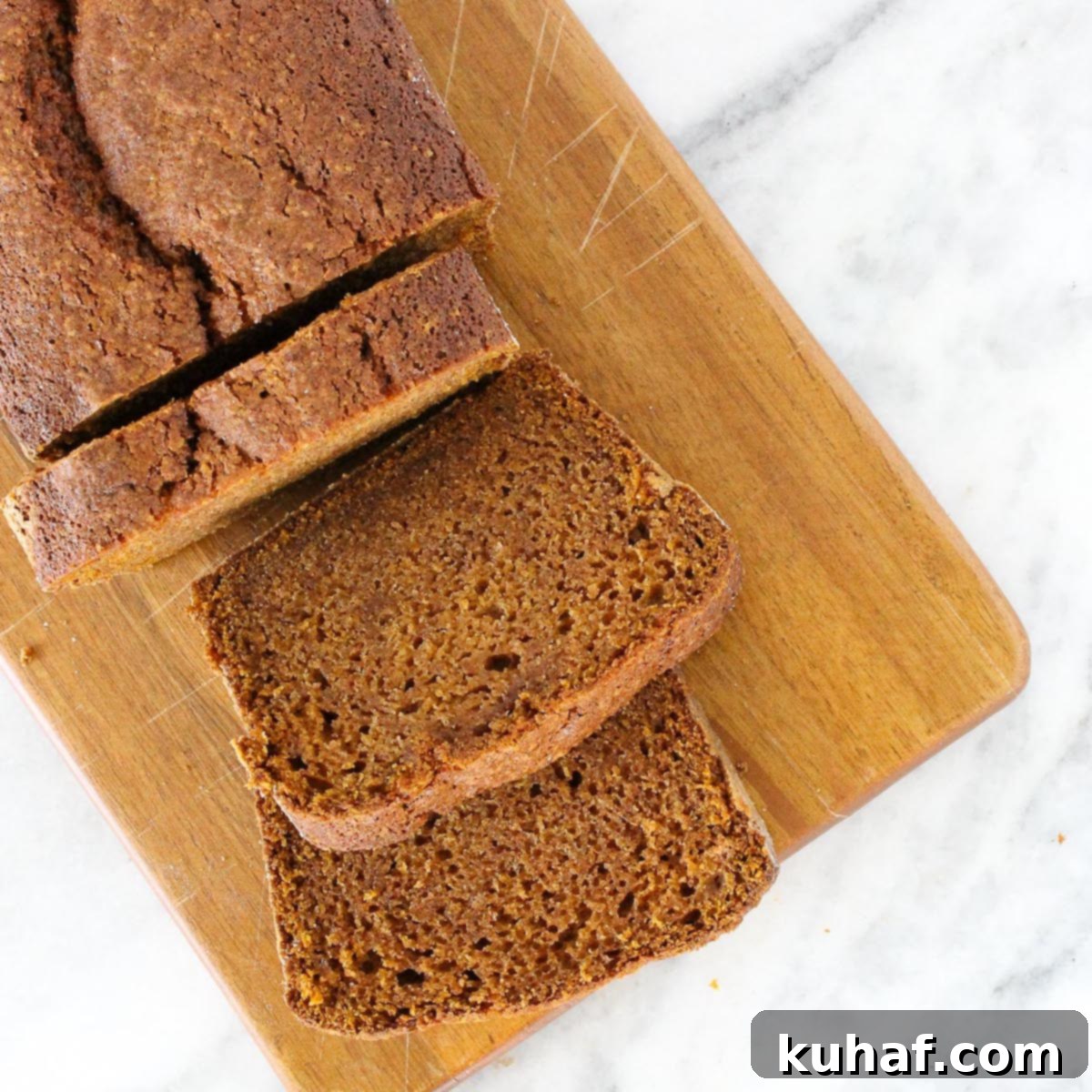 pumpkin bread slices wooden board on marble counter.
