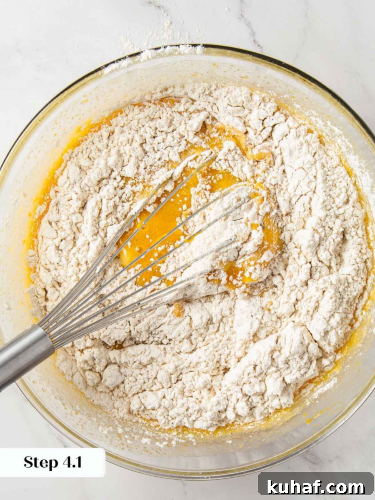 Wet and dry ingredients for pumpkin bread being mixed together.