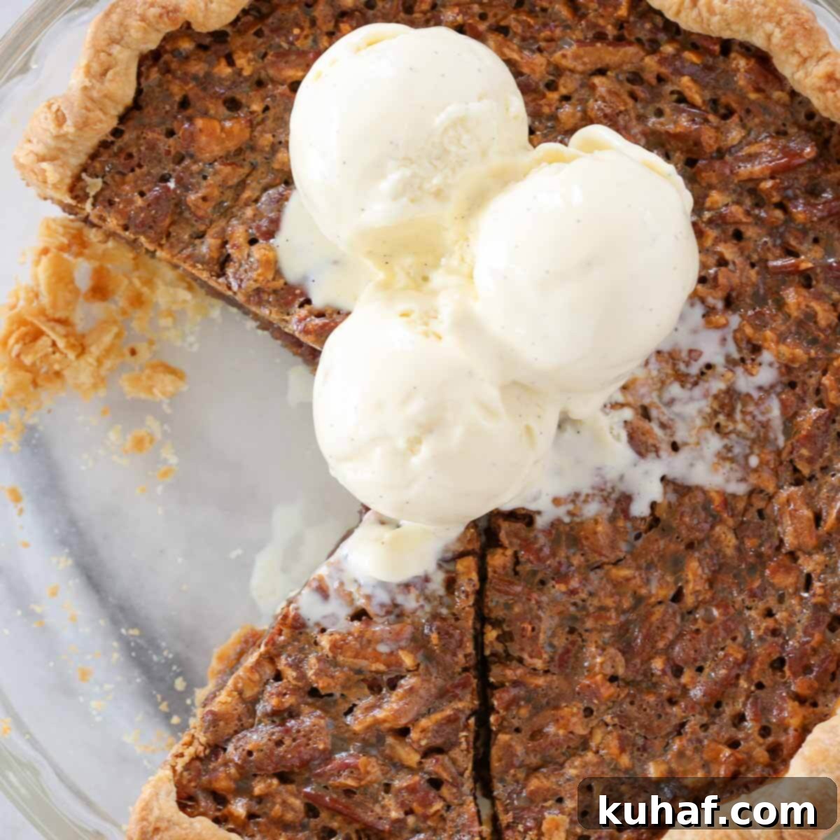 pecan pie sliced in dish with scoops of vanilla bean ice cream on top. 