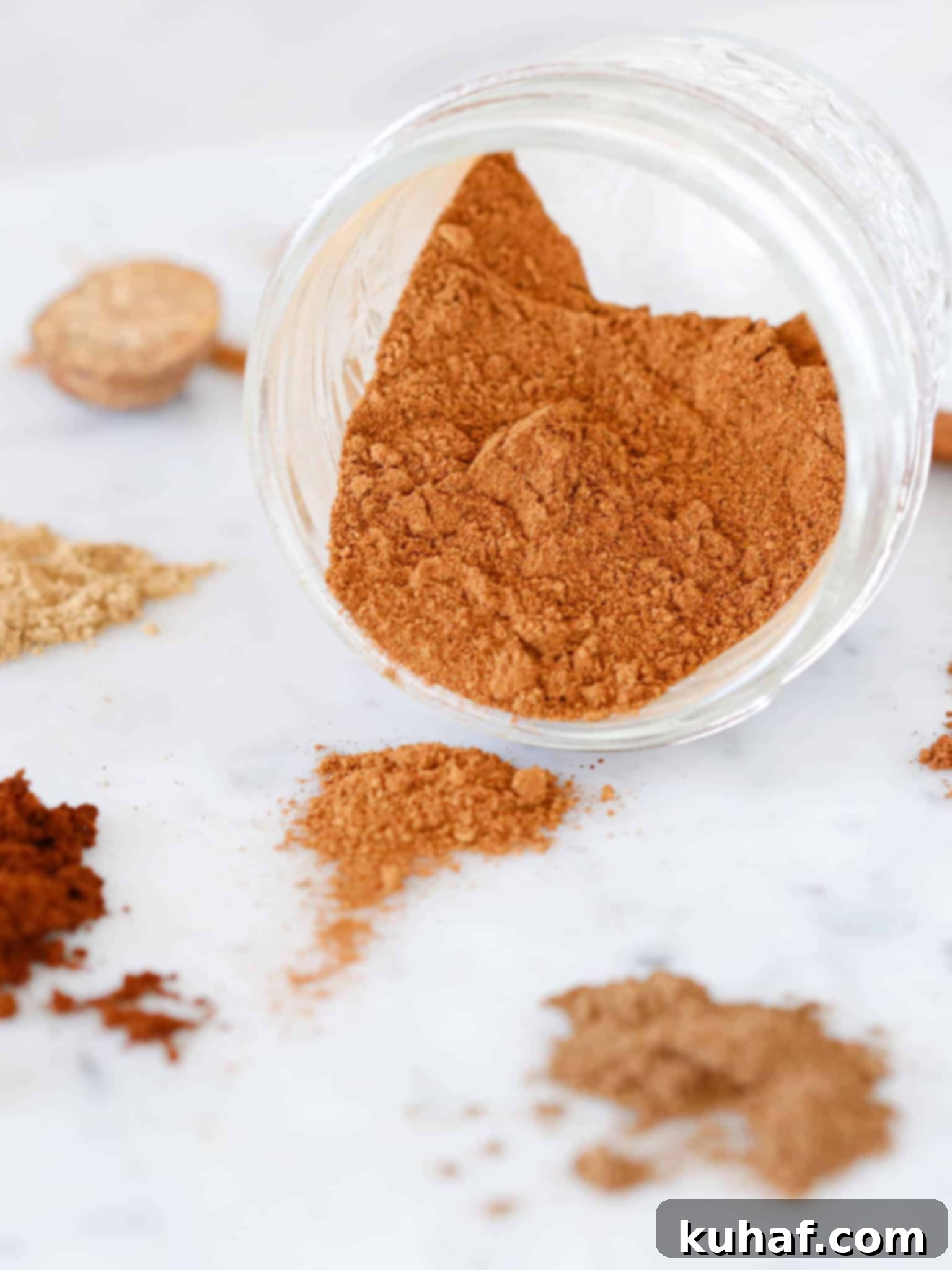Pumpkin spice mix spilling out of a rustic jar, with whole spices scattered around.