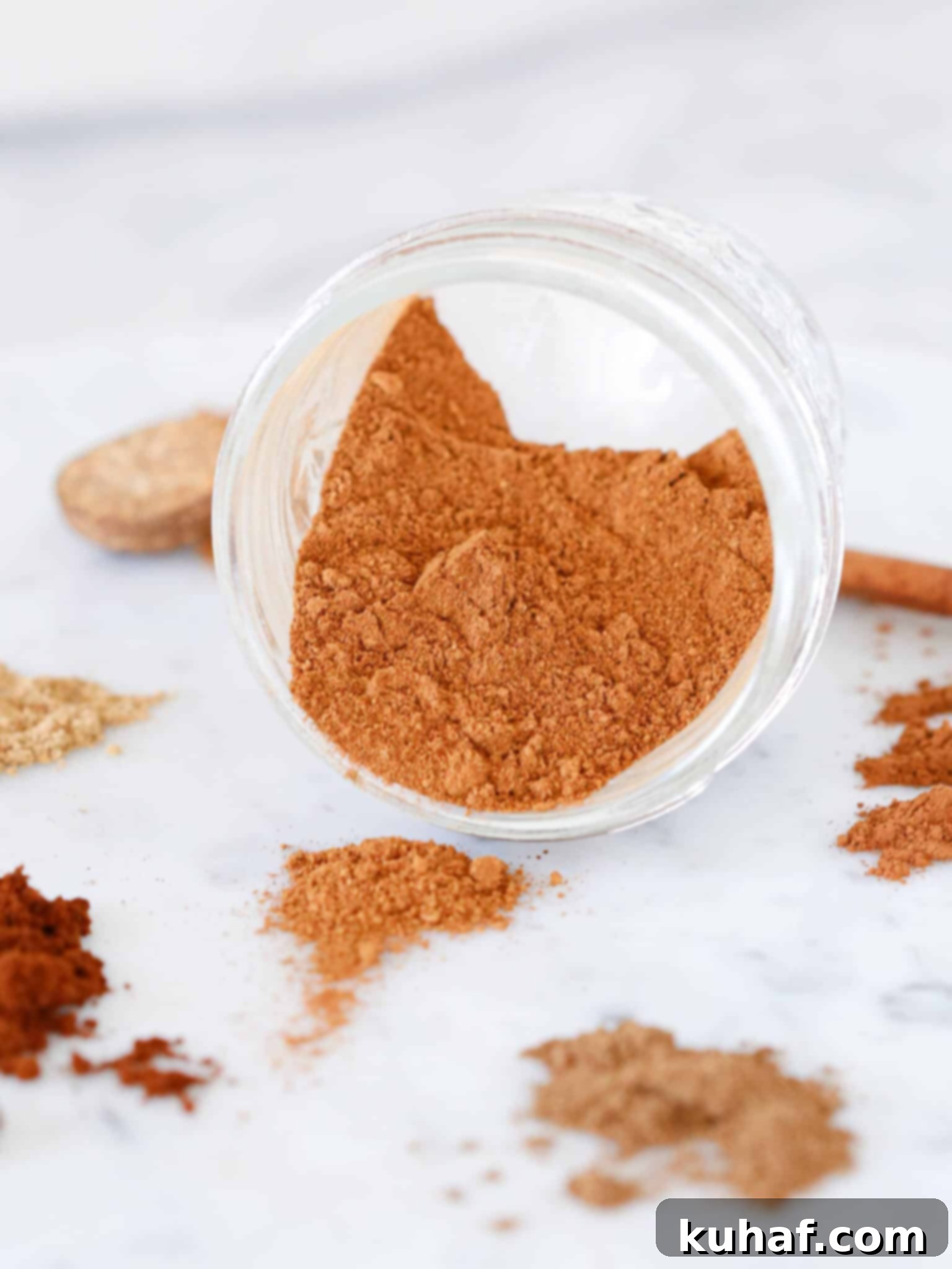 Mixed pumpkin spices in a clear glass jar with a small spoon, ready for use.