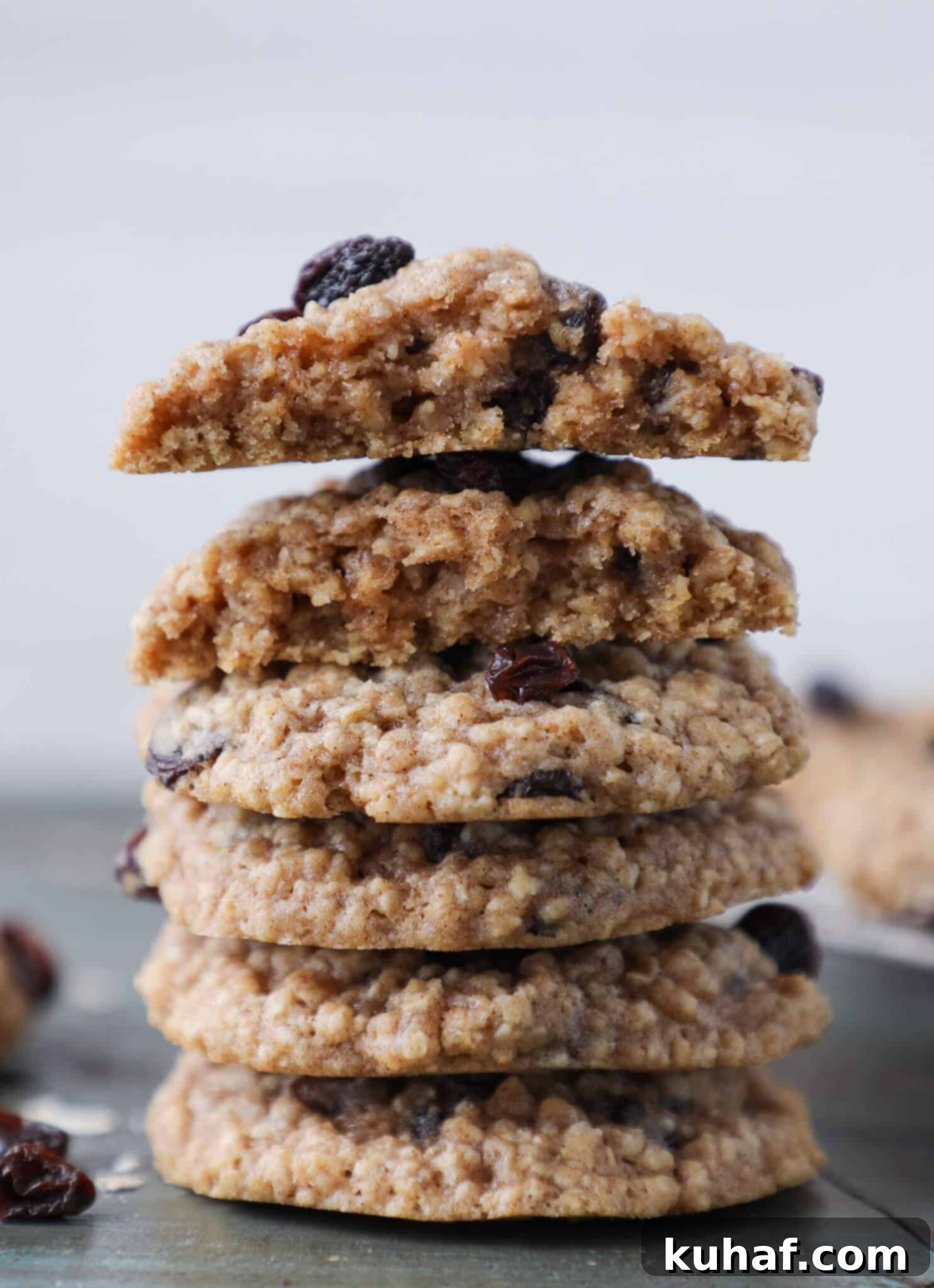 A stack of oatmeal cookies with the top two cookies broken in half, revealing their soft, cakey interior.