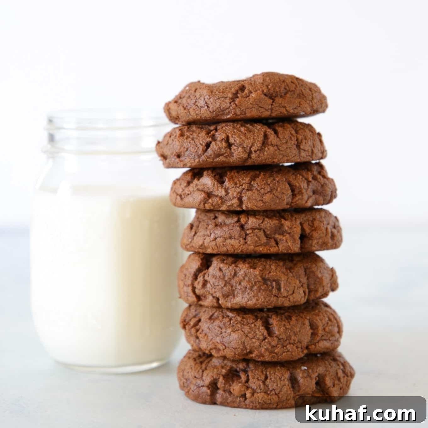 Double chocolate chip cookies next to a glass of milk.