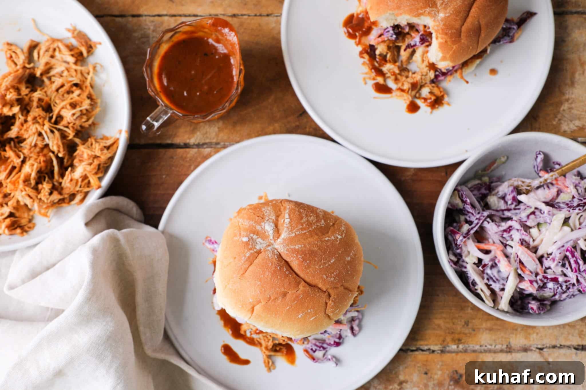A tablescape featuring slow cooker barbecue pulled chicken sandwiches, sweet coleslaw, and other delicious side dishes, set for a casual meal.