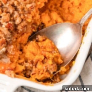 Decadent Sweet Potato Casserole with Crunchy Pecans 12 sweet potato casserole being served with spoon.