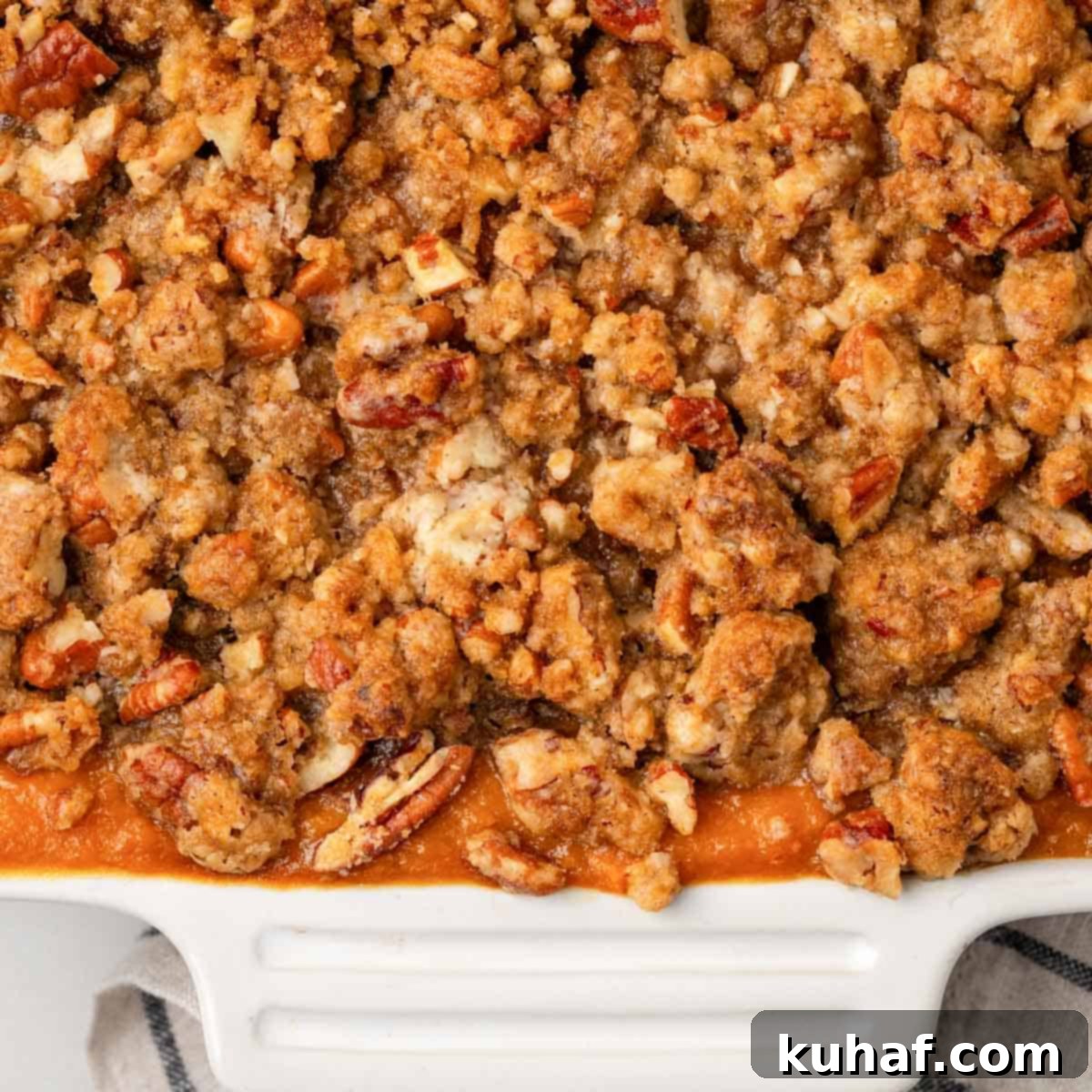 Decadent Sweet Potato Casserole with Crunchy Pecans 3 Golden-brown baked sweet potato casserole in a white serving dish, ready to be enjoyed.