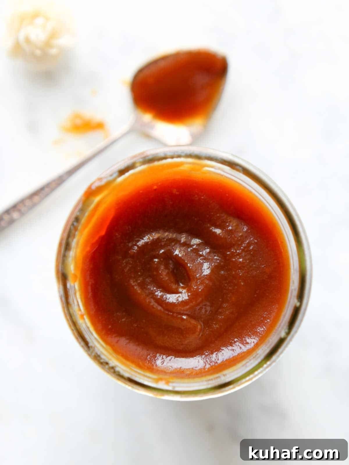 Caramelized Apple Spread 2 Silky smooth homemade apple butter in a jar on a marble surface, ready to be enjoyed.