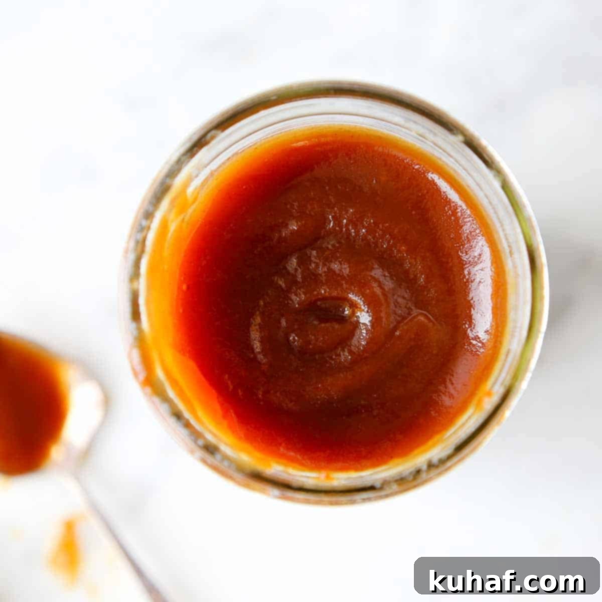 Caramelized Apple Spread 10 Swirls of homemade apple butter in a clear jar, showcasing its smooth texture and rich color.