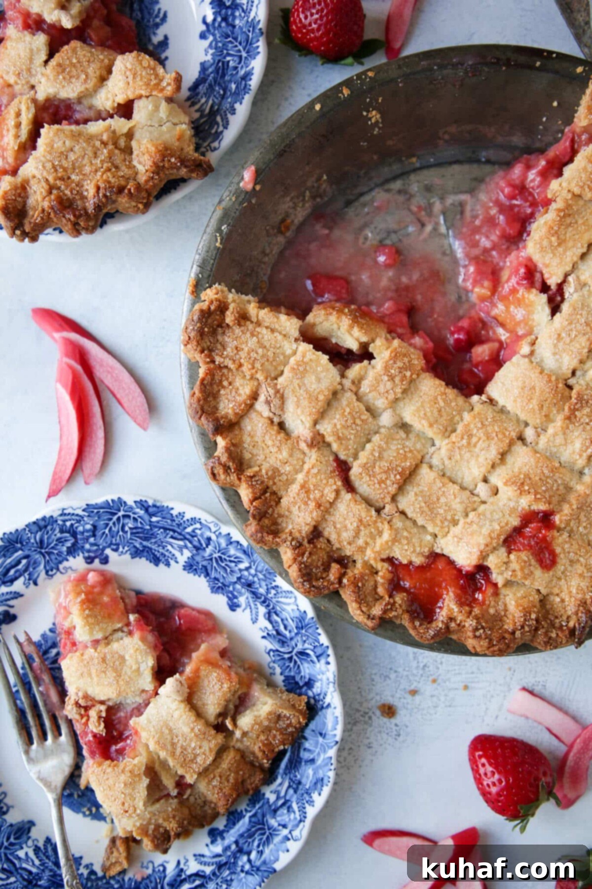 Strawberry Rhubarb Pie in almond lattice crust with two slices on blue plates.