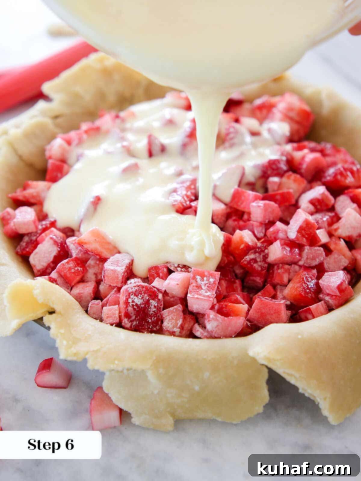 Pouring egg sugar mixture over strawberries and rhubarb.