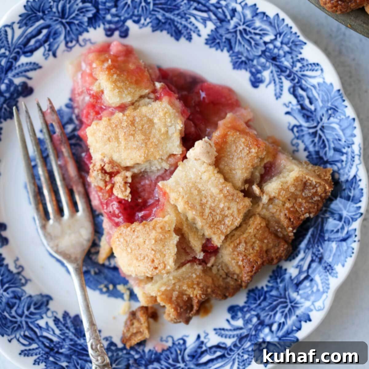 slice of strawberry rhubarb pie on blue plate.