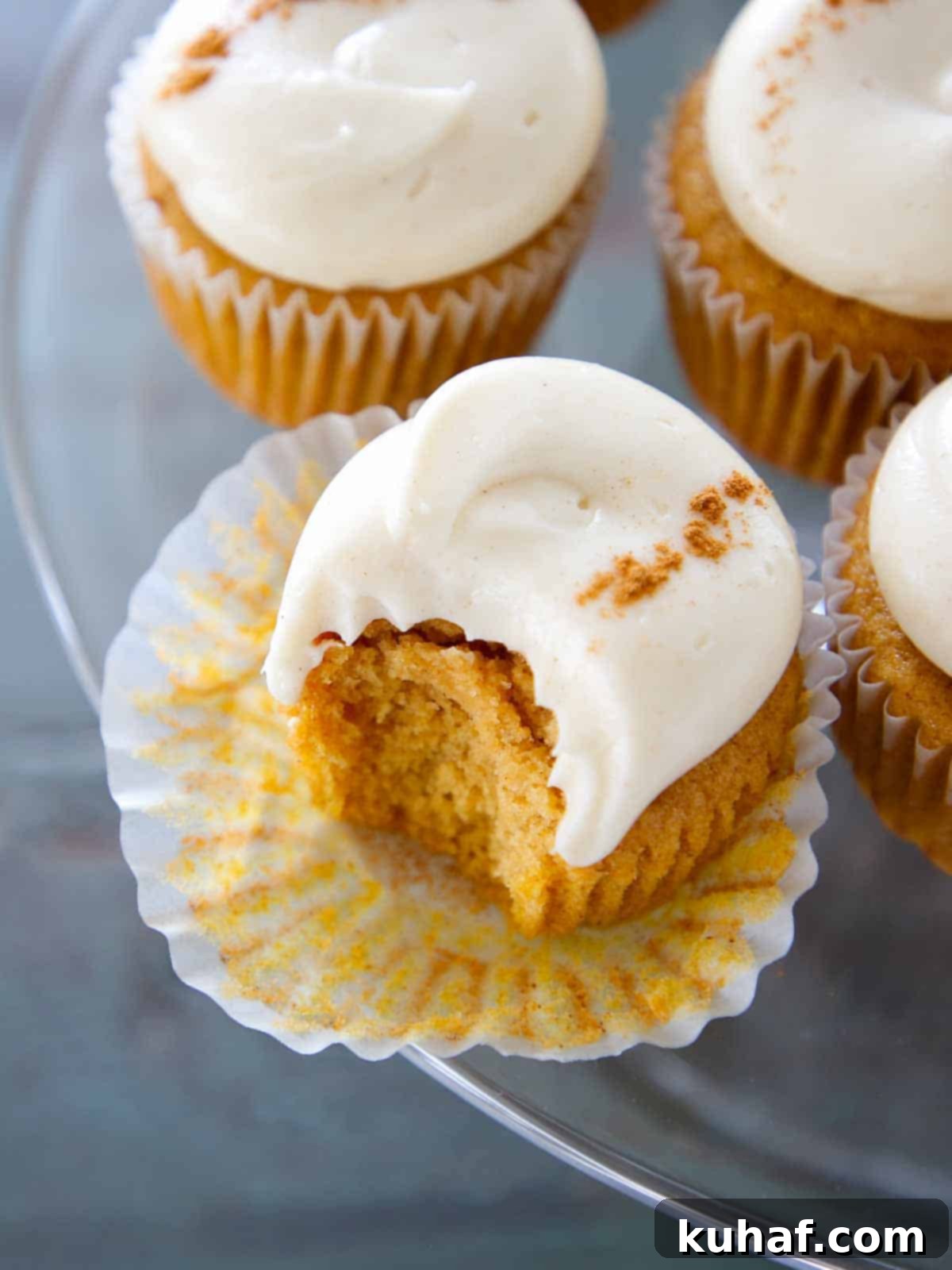 spiced cream cheese buttercream on pumpkin cupcakes on cake stand.