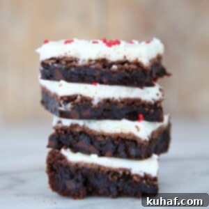 Peppermint Triple Chocolate Brownies stacked with a dusting of powdered sugar and crushed candy canes.