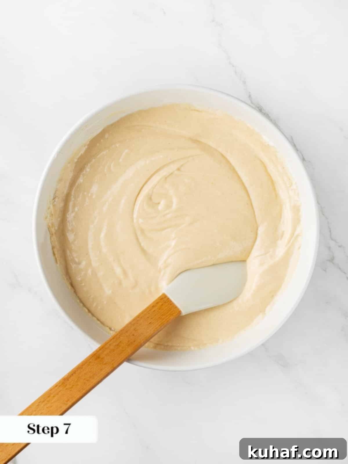 Mixing cranberry cake batter with a silicone spatula inside a large bowl.