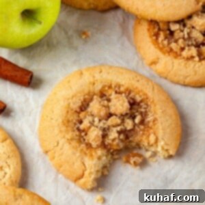 A single apple pie cookie with a bite taken out, revealing its wonderfully chewy brown sugar dough and a luscious, spiced apple filling.