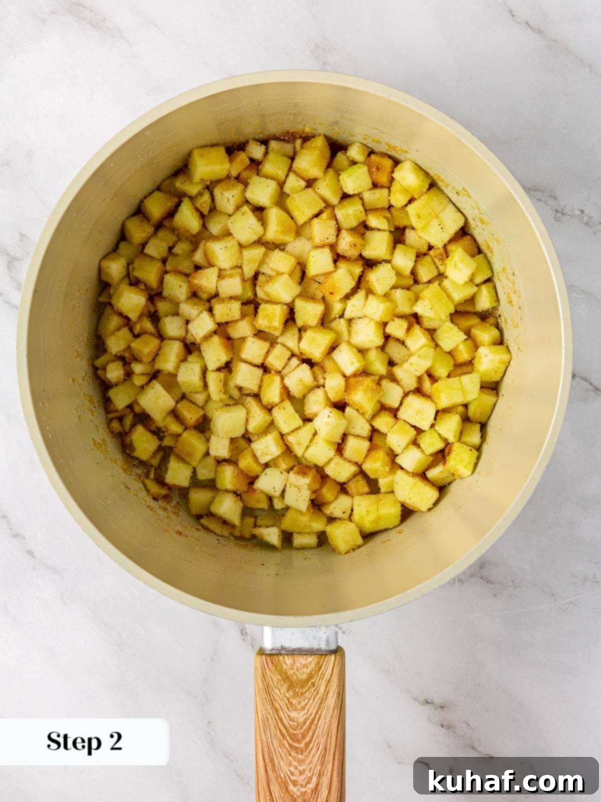 Chopped Granny Smith apples being cooked down in a saucepan with brown sugar and fresh lemon juice, starting to soften for the pie filling.