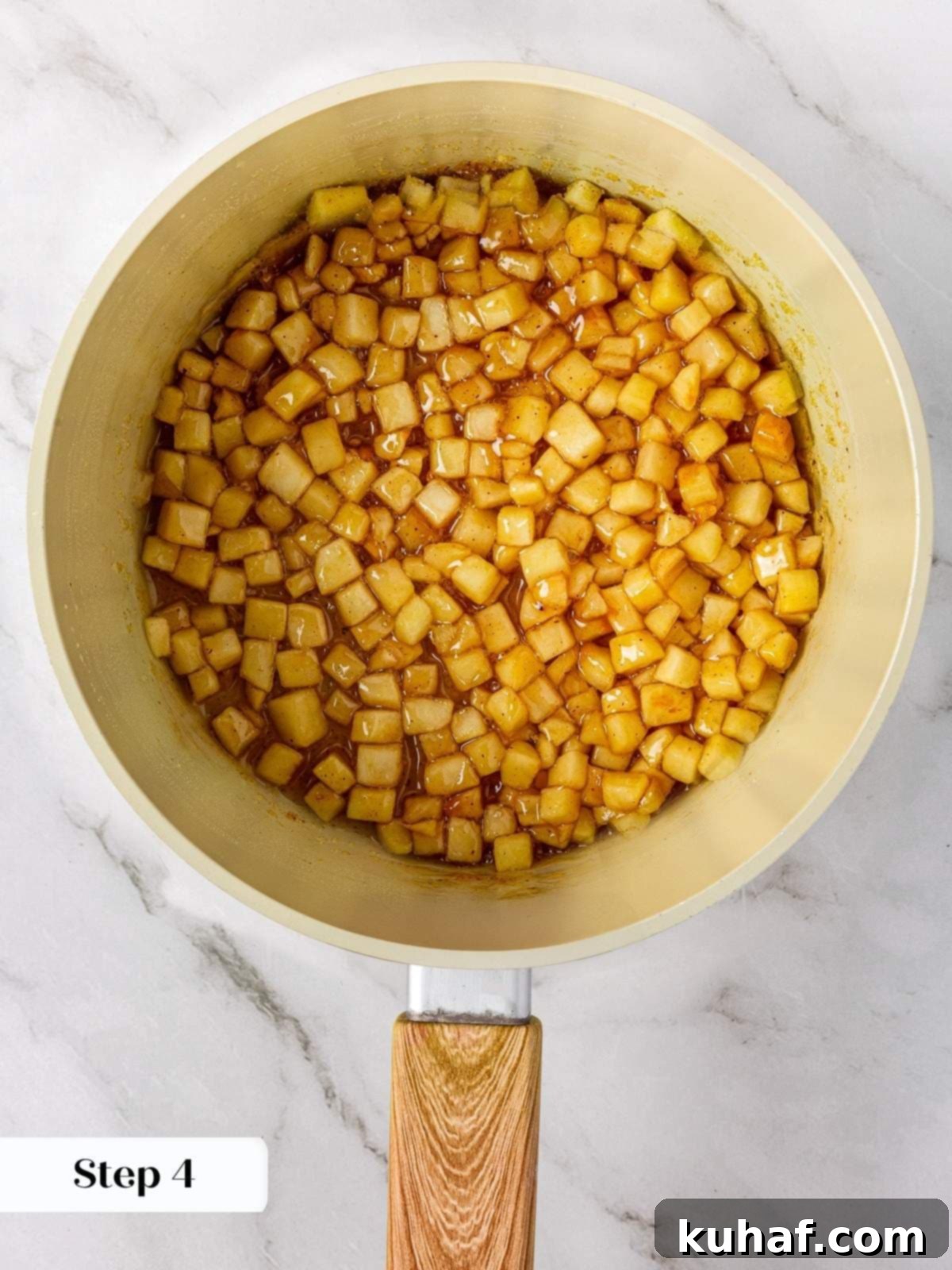 Diced apples bubbling gently in a rich, cinnamon-spiced sauce inside a stainless steel saucepan, thickening beautifully.