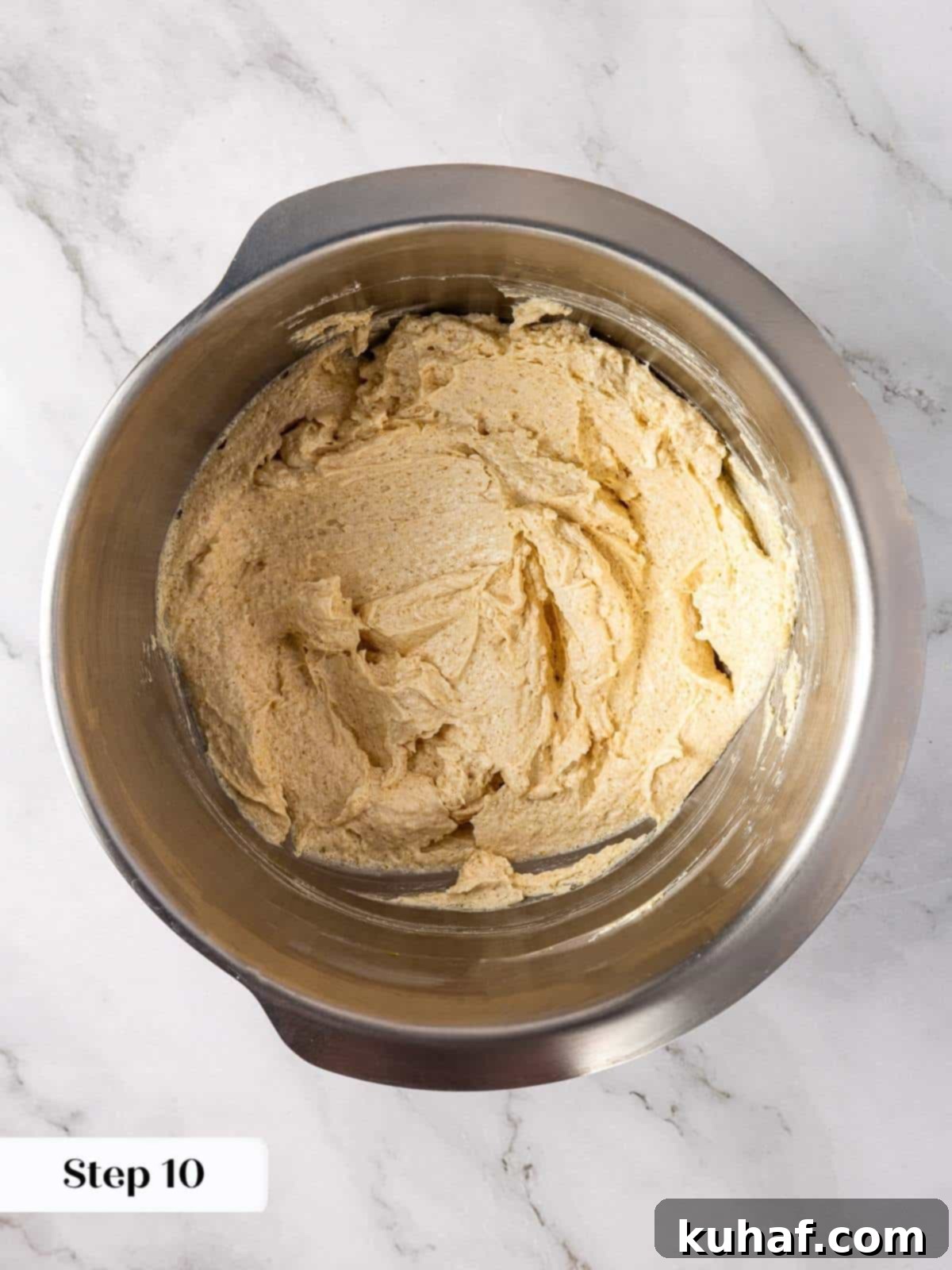 A mixing bowl where a large egg and vanilla extract are being vigorously stirred into the creamy brown sugar and butter base, preparing for the next stage of cookie dough.
