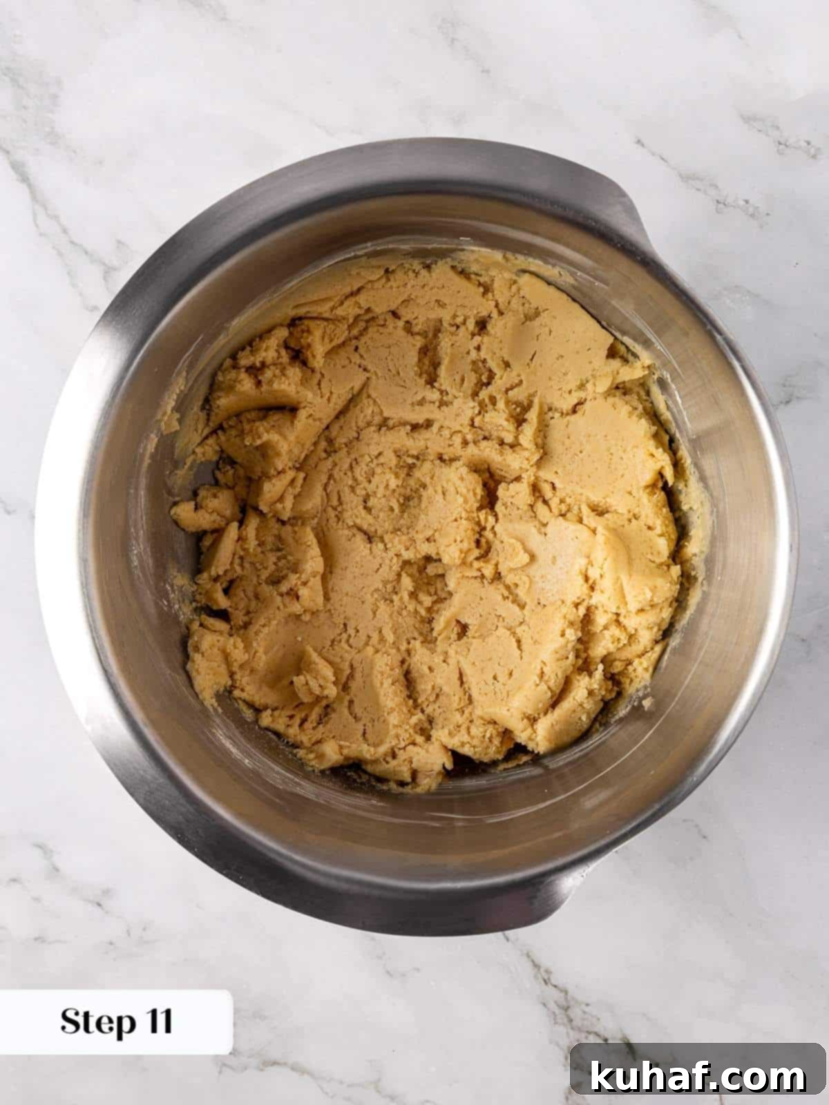 The fully mixed apple cookie dough resting thick and pale in a large mixing bowl, ready to be scooped and prepared for filling.